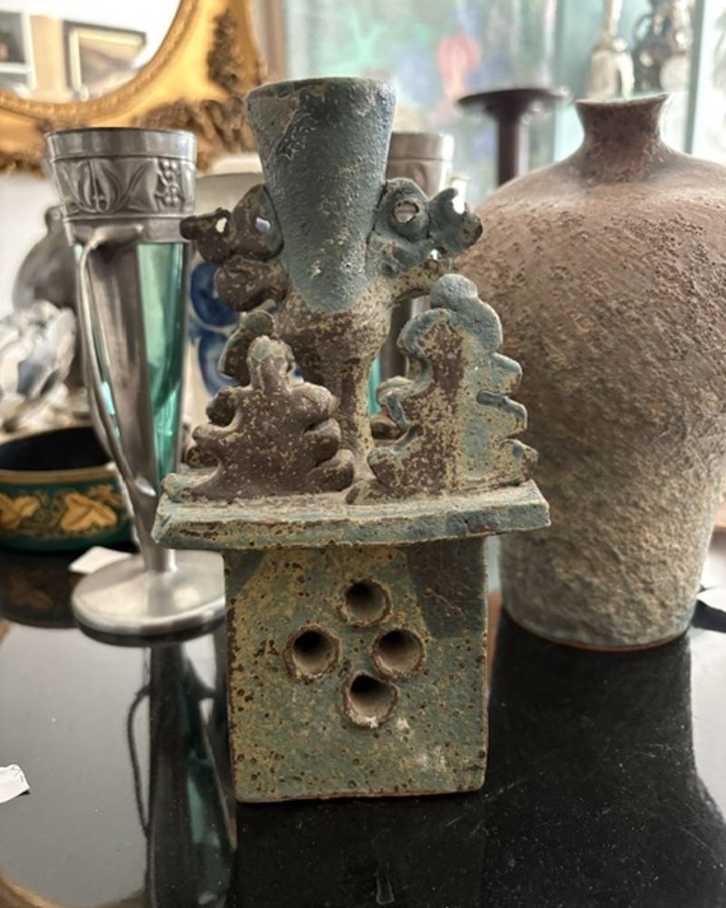 Cluttered phone snapshot of a stoneware candle holder on a shop table